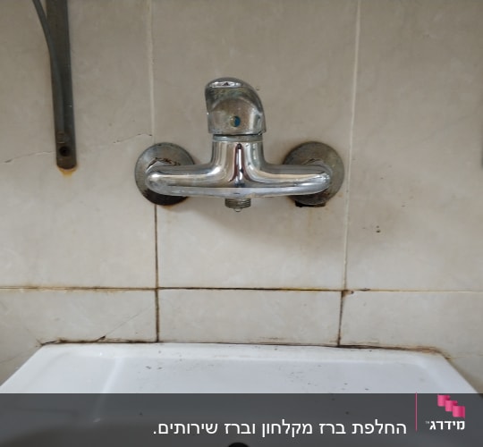 ברז מתכת מותקן על קיר אריחים לבנים